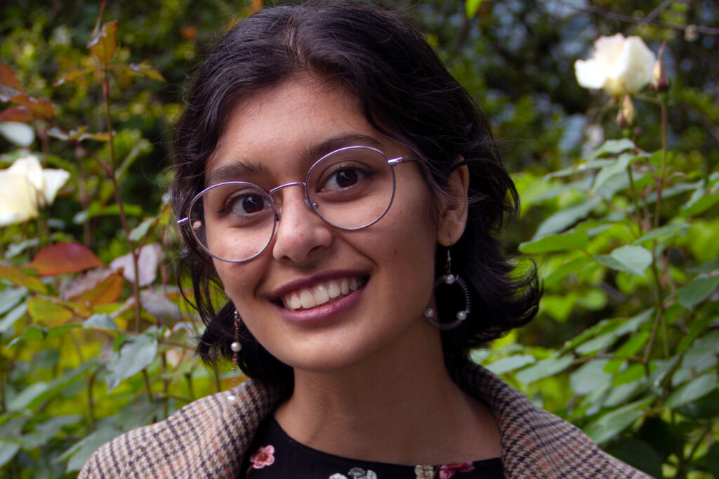 A casual portrait of Corina Dunn, smiling, against a rose-garden backdrop.