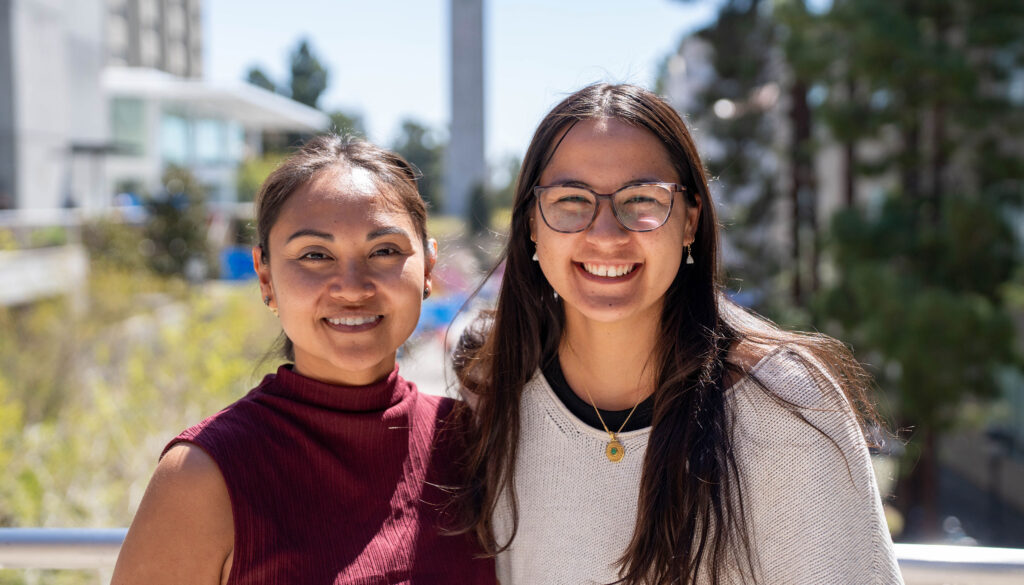 Two people stand outdoors on the Berkeley campus during a sunny spring day.