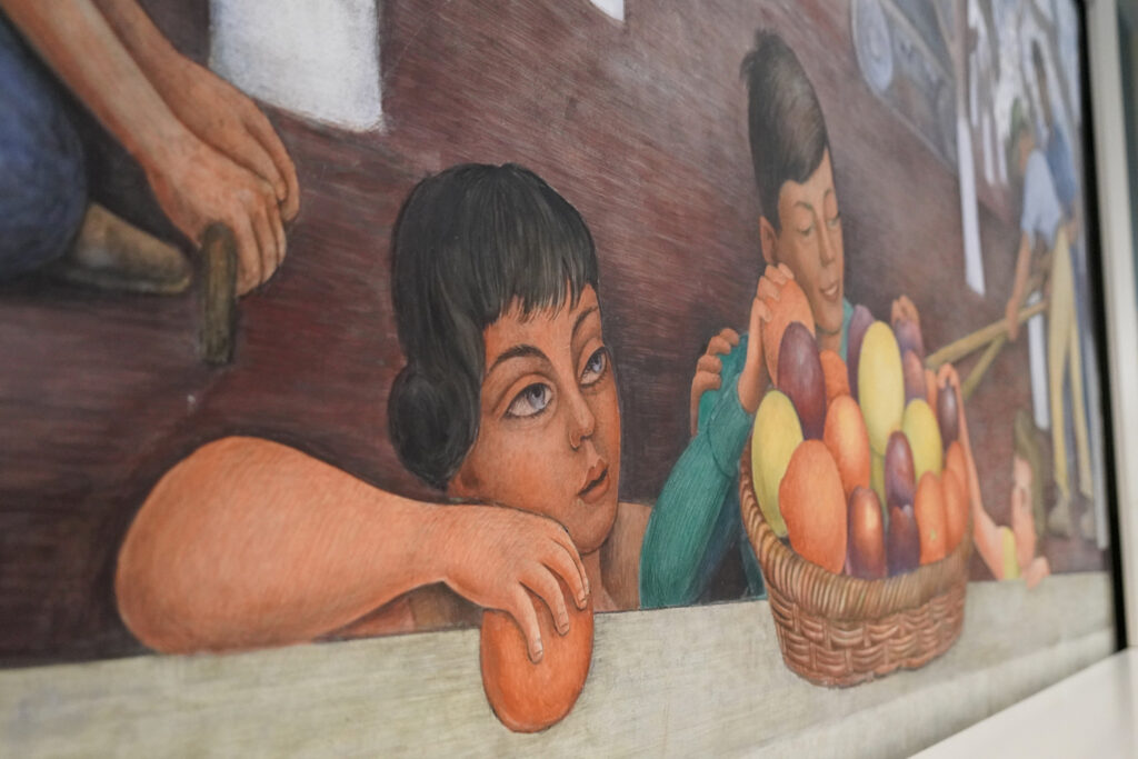A detail from a Diego Rivera mural in Doe Library shows youngsters grasping for fruit that was picked in a California orchard.