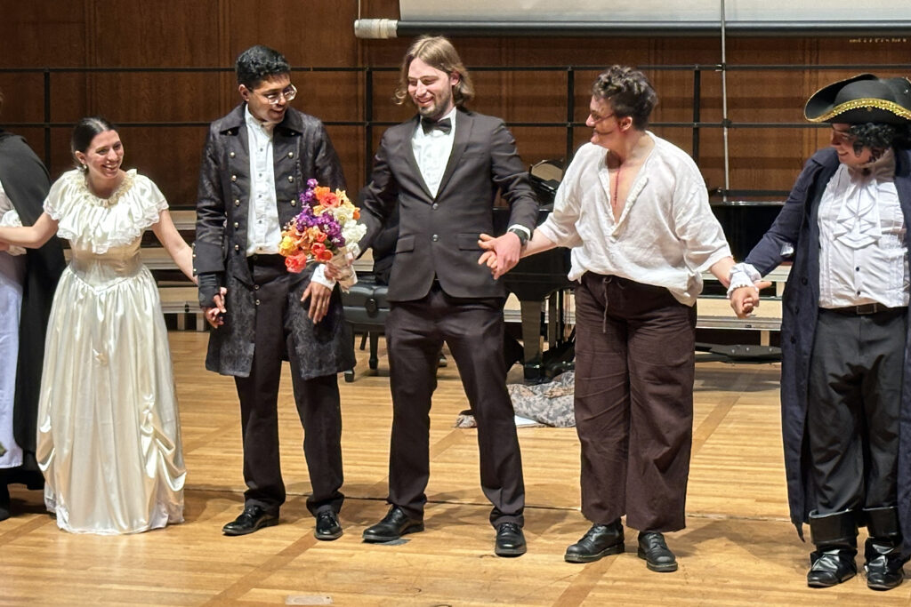 Owen Klein, wearting a tuxedo and holding a bouquet of flowers, stands on stage with costumed cast members of "Frankenstein," the opera he composed, wrote and directed.