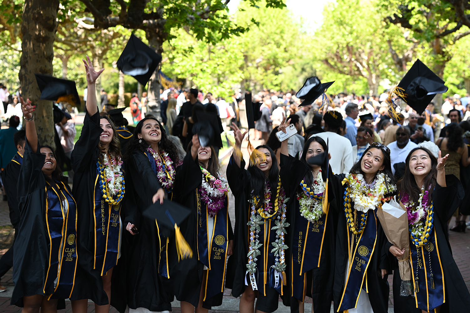 A group of graduates tosses their mortarboards into their air outside California Memorial Stadium on May 17, 2025, before the campuswide commencement.