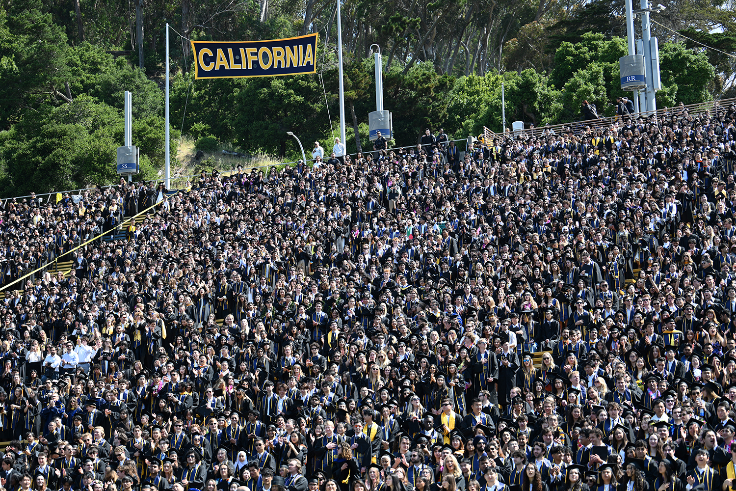 Thousands of people stand in the bleachers at California Memorial Stadium to cheer the graduates at the 2025 campuswide commencement.