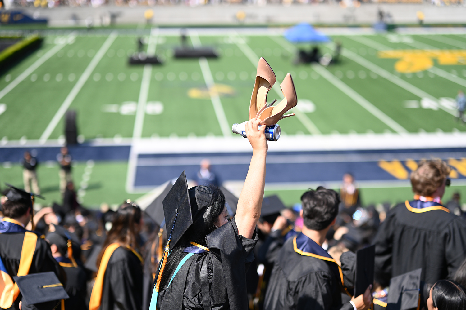 A student holds up a pair of stiletto heels at the 2025 campuswide commencement.