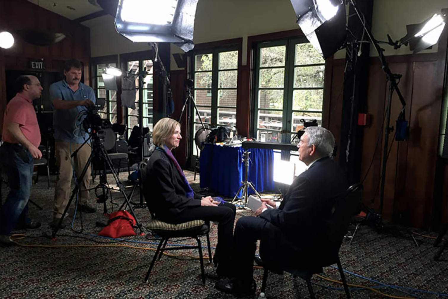 Professor Jennifer Doudna, wearing a black pantsuit, sits in a chair facing CBS News reporter Dan Rather during an interview about her discovery of CRISPR.