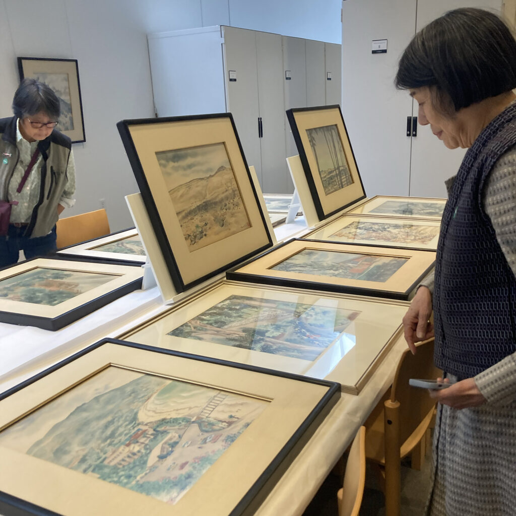 Two sisters look at framed artwork done by their grandfather, Chiura Obata, that were laid out on tables and on walls at the Berkeley Art Museum and Pacific Film Archive.