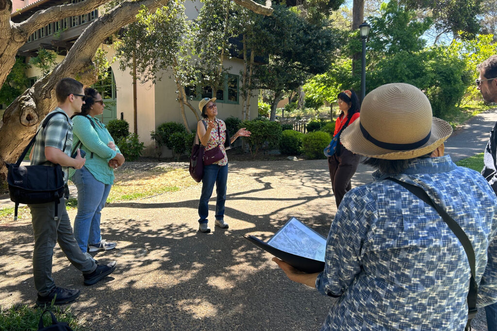 A group of people stands on campus as two women talk with them about the life of Chiura Obata, a famous painter and UC Berkeley faculty member who was forced to leave campus during World War II for an internment camp.
