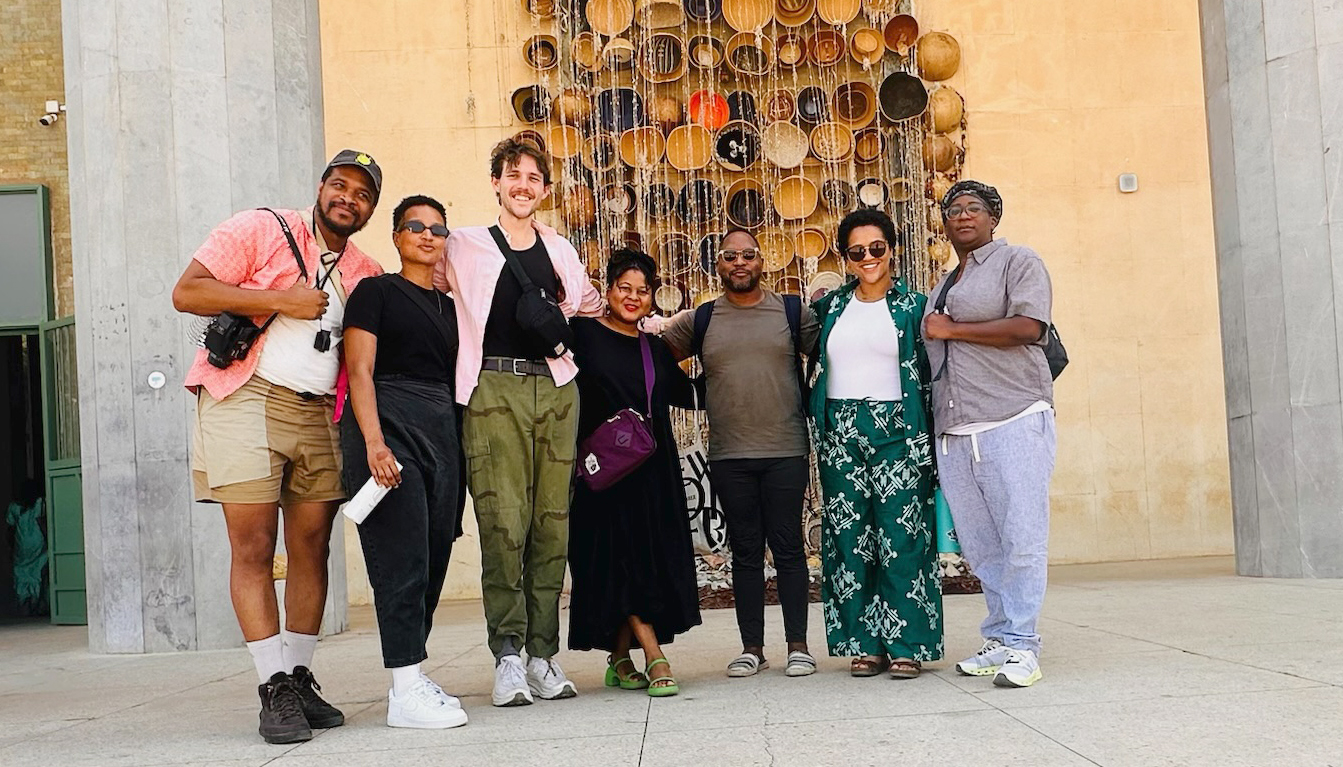 A group of seven UC Berkeley scholars stand in front of an art piece during their travel seminar to Senegal