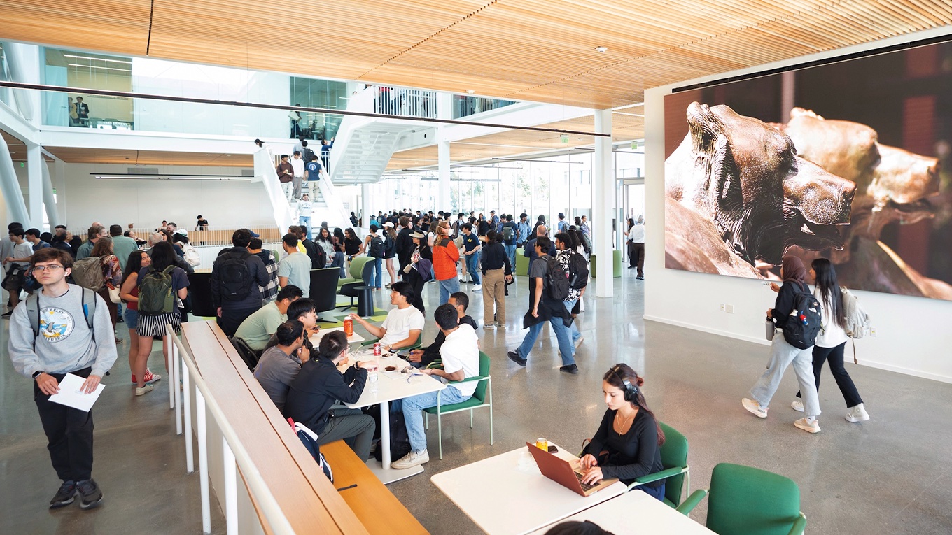 Crowds of students are gathered in a sunny atrium in UC Berkeley's Grimes Engineering Center.
