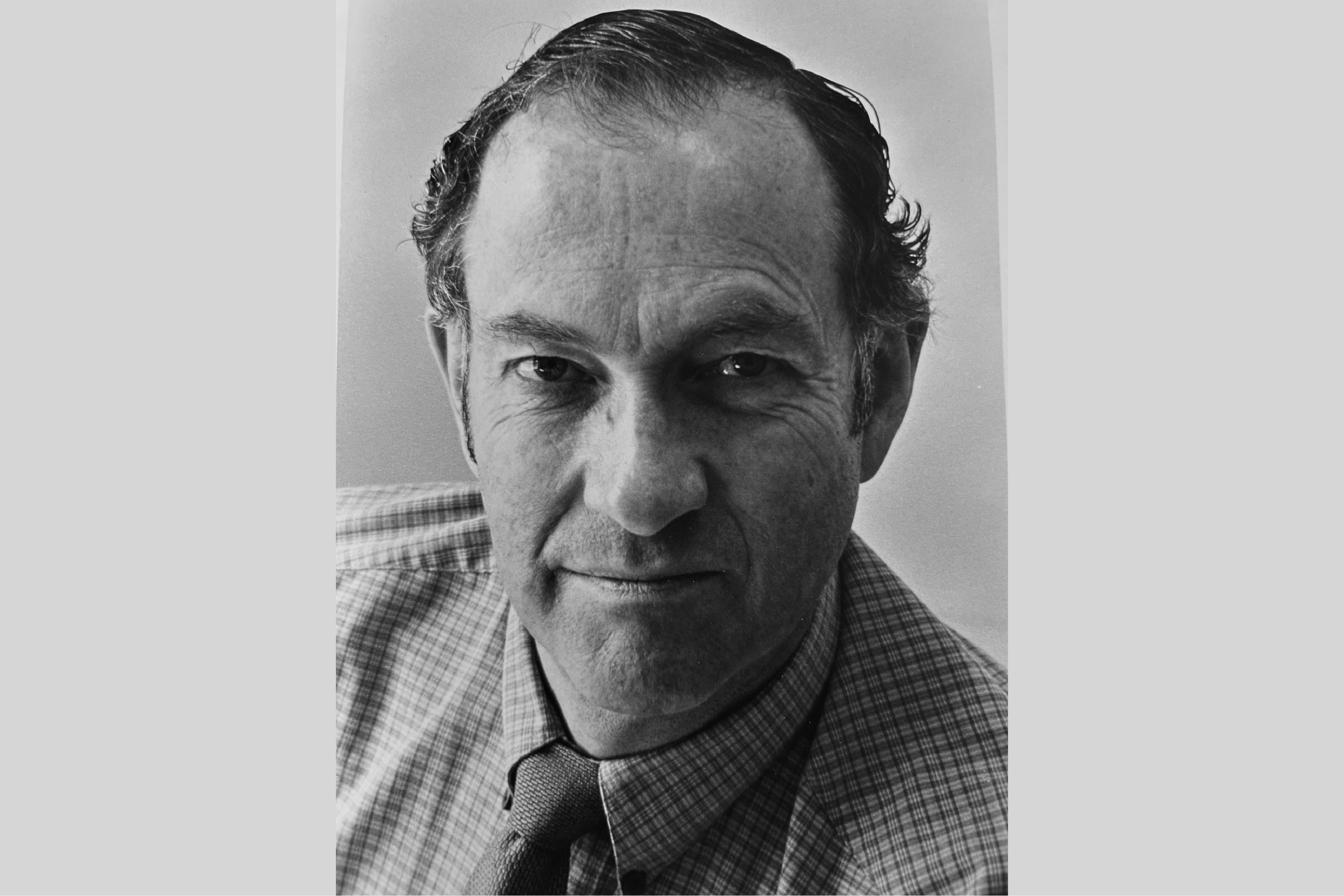 Ray Colvig, director of Berkeley's news office from 1927-1991, looks straight ahead and slightly balding and wearing a plaid shirt with a tie.