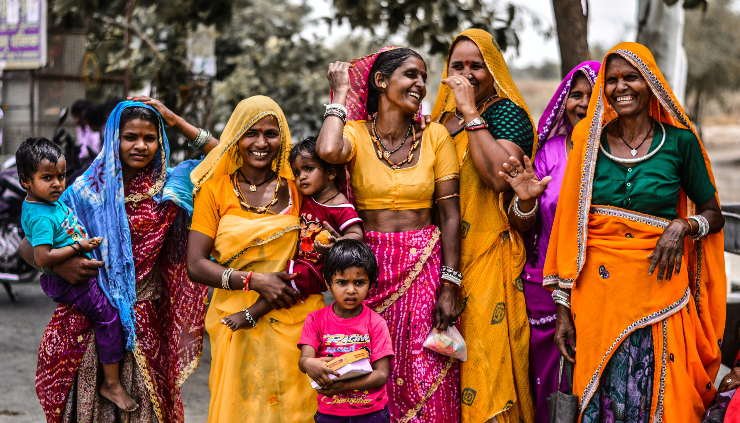 a line of Indian women in colorful saris, with their children