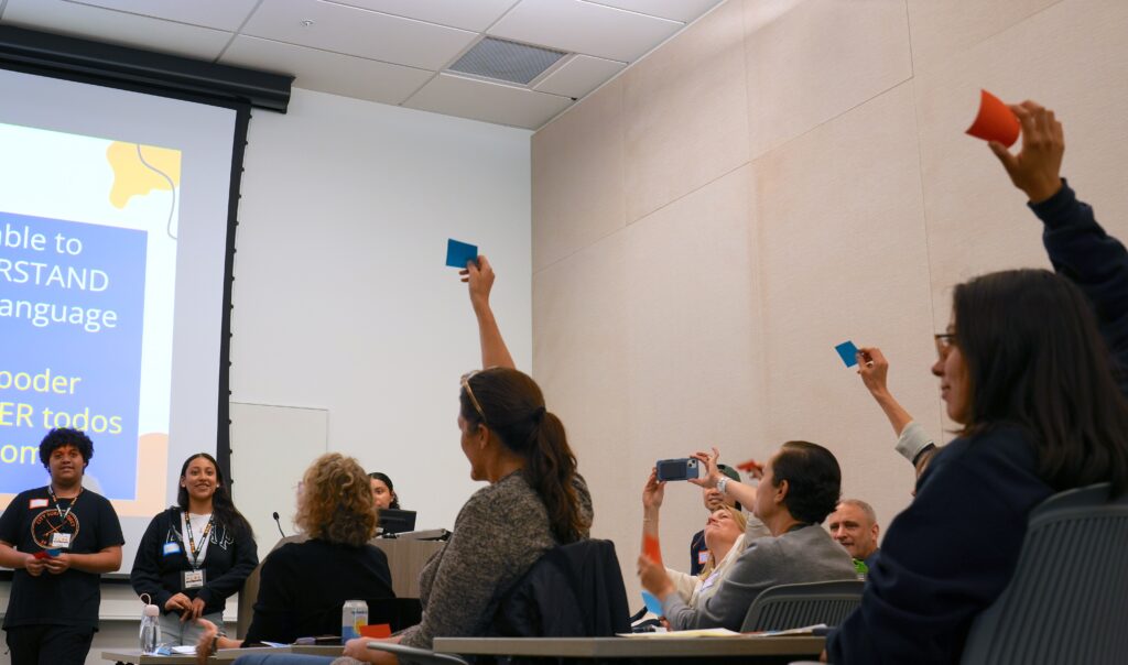 People raise red or blue cards during a high school student-led activity on the Berkeley campus