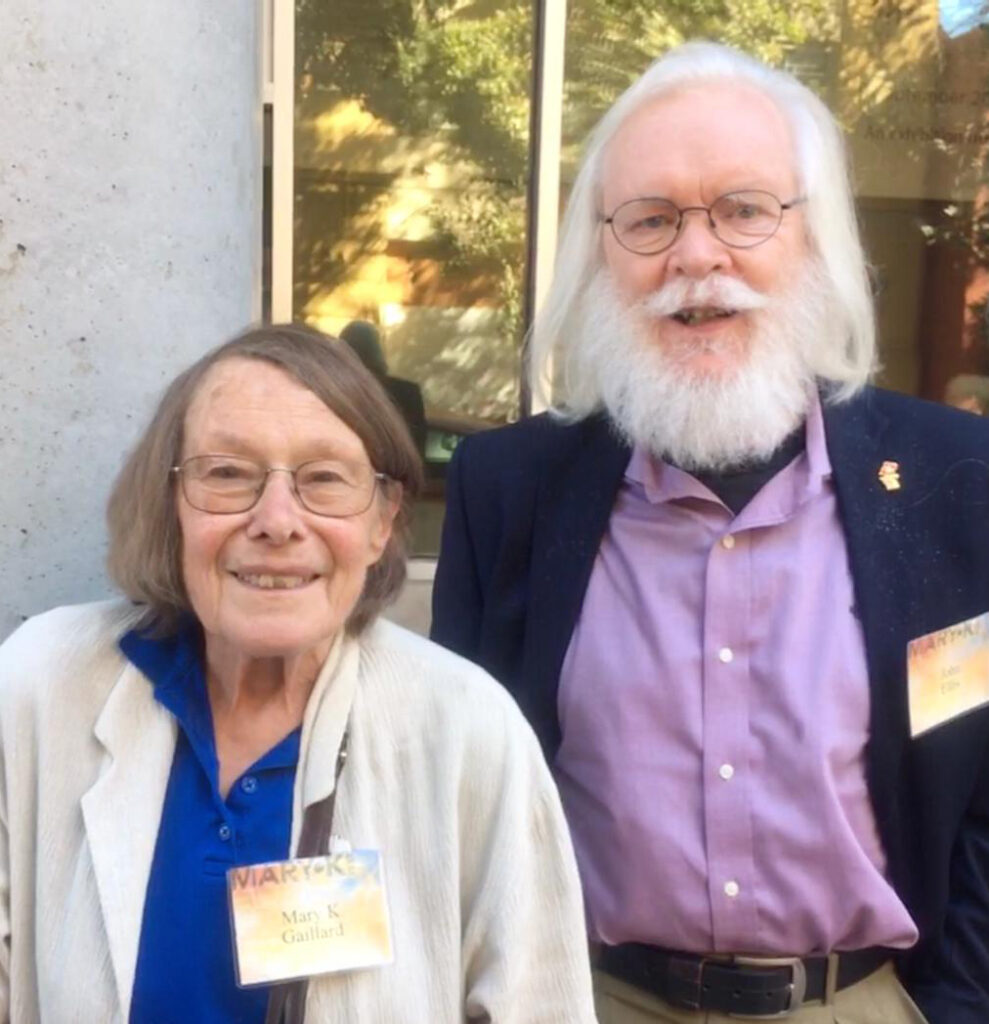 a woman and a white-bearded man looking at the camera