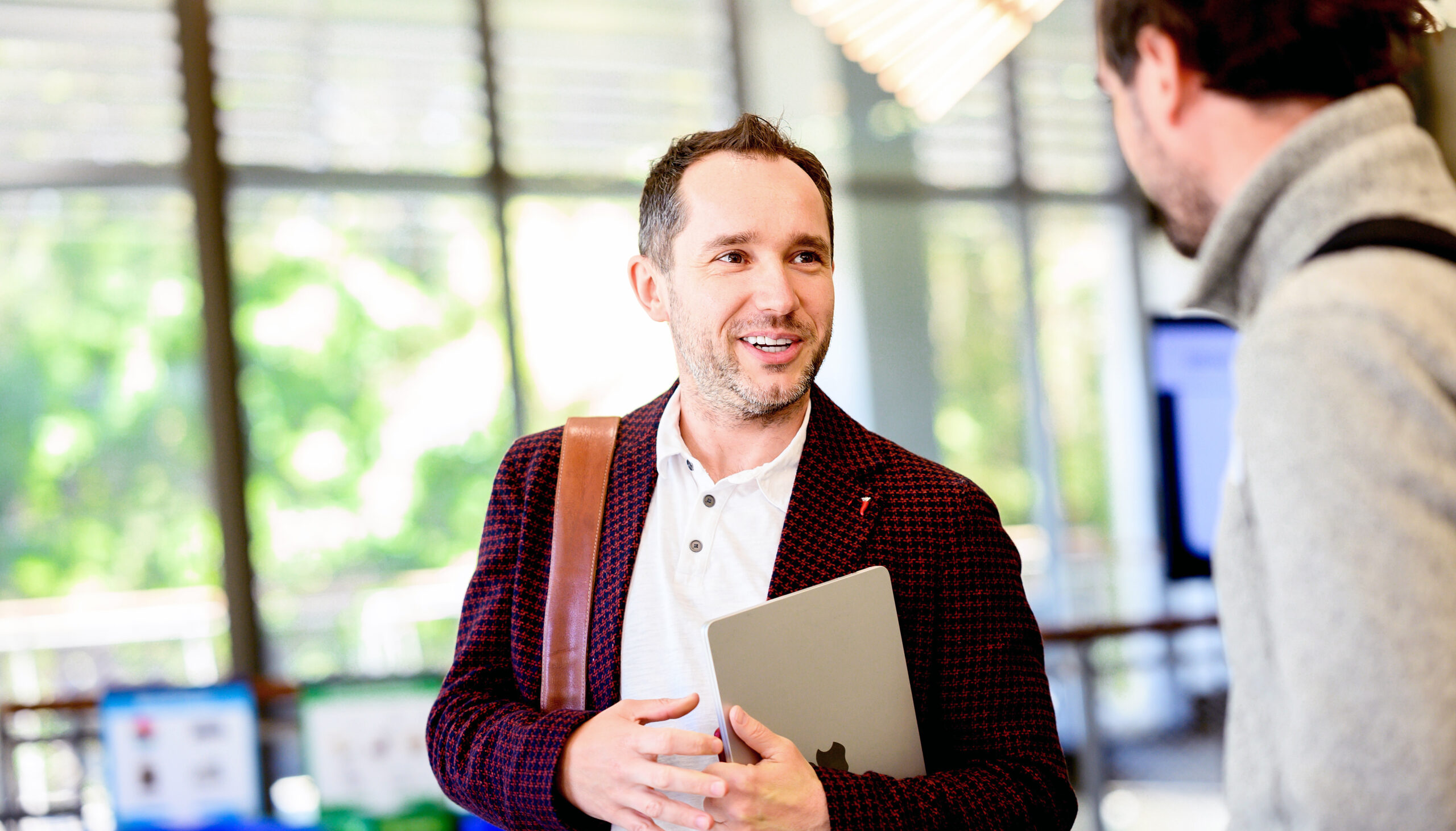 Przemyslaw Jeziorski, in an atrium bright with natural light, speaking casually with student after class