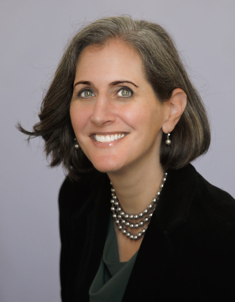 headshot of Amy E. Lerman, wearing a black suit against a grey background.
