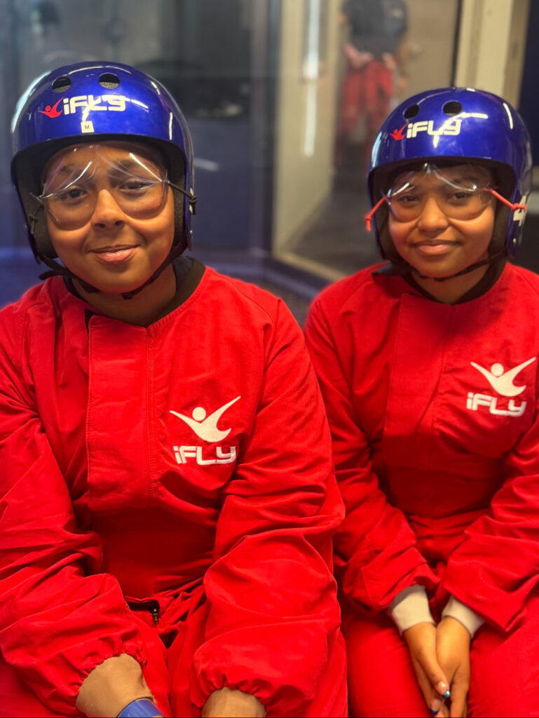 Two students wearing red jump suits, helmets and goggles