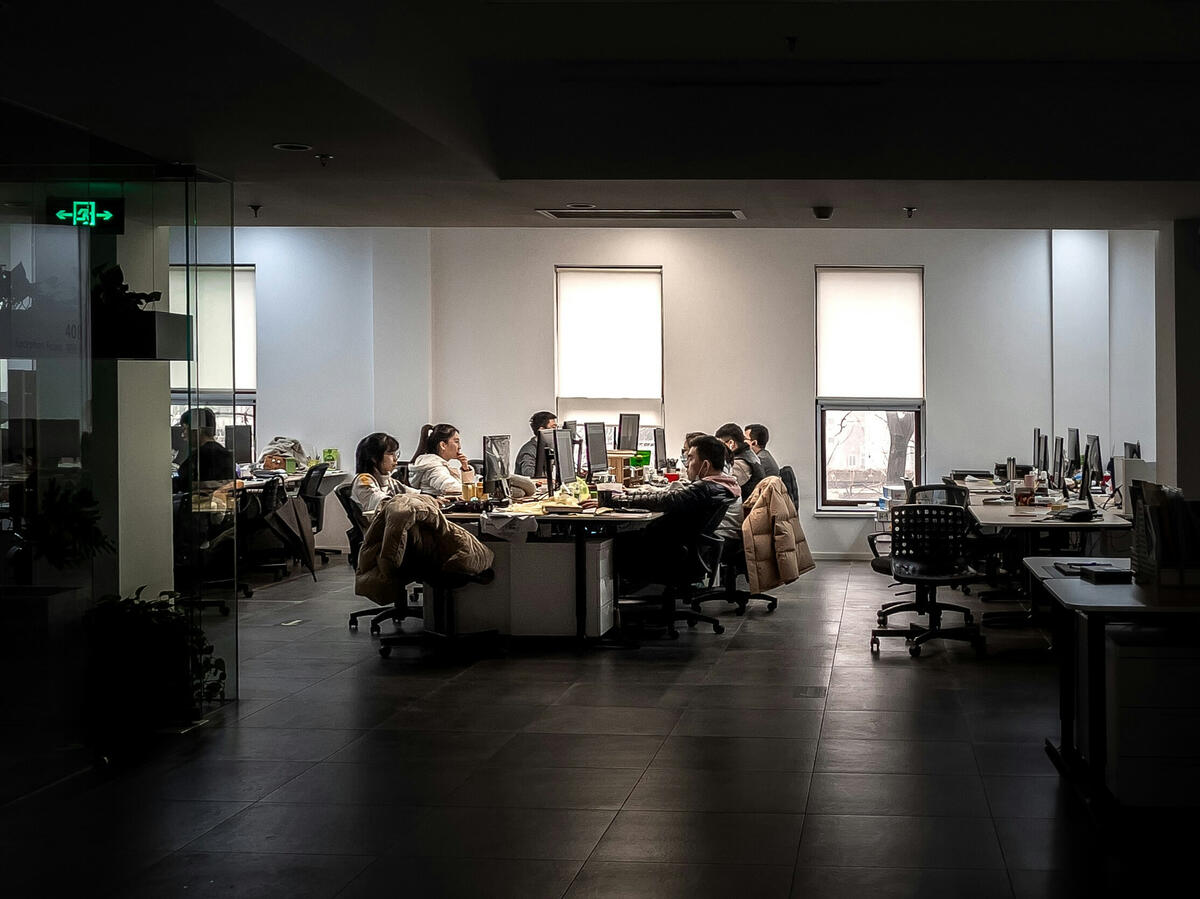 people sitting in an open-floor-plan workspace looking at computer monitors