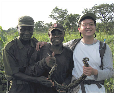 Matt Fujita in Kyabobo National Park, Ghana, posing with assistants Baturi Ali and Propser and a python.