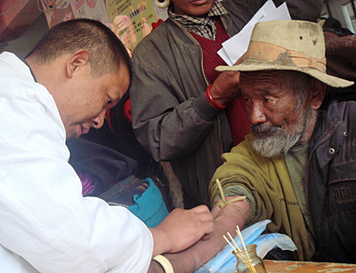 Chinese technician collecting blood from Tibetan man