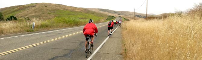 Cyclists in red climb a stretch of highway