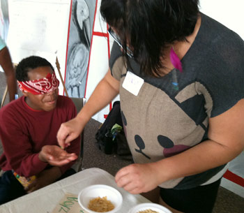 Magnolia Project volunteer Ingrid Villarreal  serves Trey, 13, different types of cereal in a blindfolded taste test. 